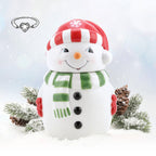 Frosty Jewel Candle - Schneemann-Duftkerze mit roter Mütze und grünem Schal im Schnee, winterliche Deko mit Tannenzweigen und Schmuck-Armband als Überraschung.